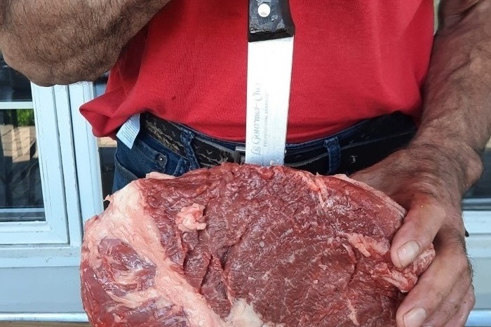 Chef de Méchoui du Marquis découpant des viandes grillées au feu de bois pour un service traiteur en plein air au Québec, lors d’un évènement festif